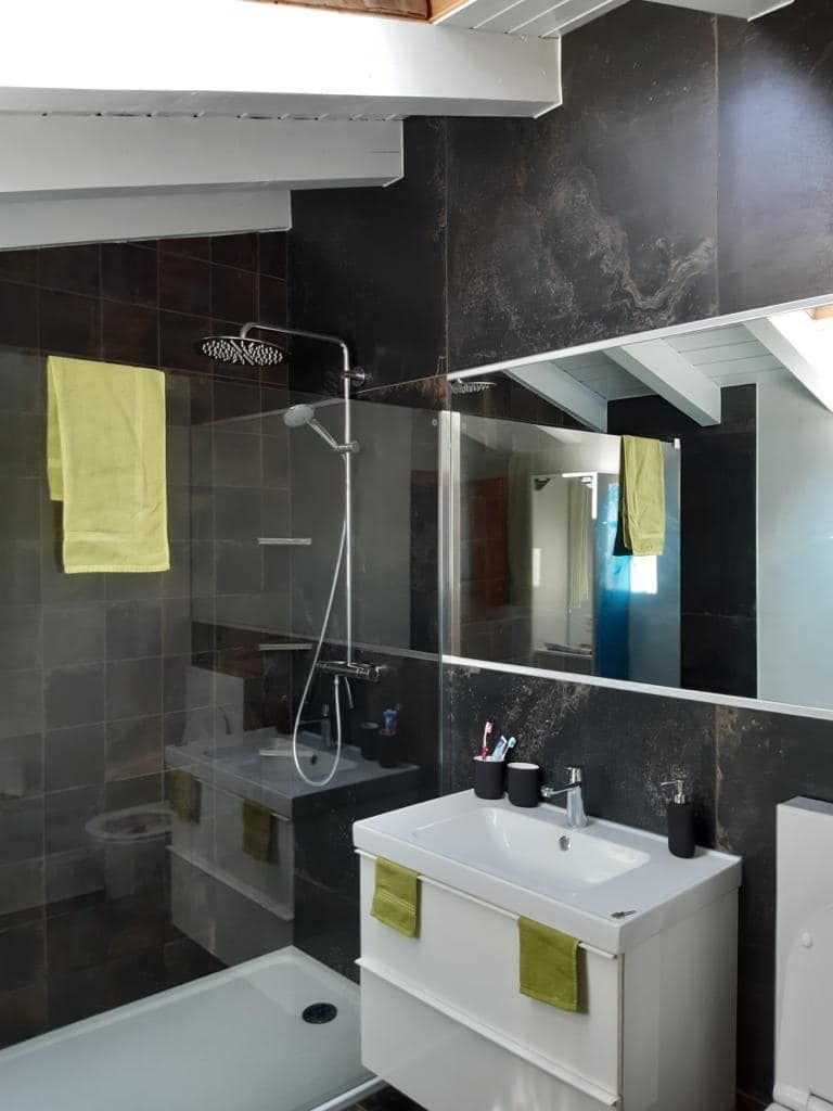Salle de bains habillée de grès cérame effet marbre noir, douche à l’italienne et paroi vitrée