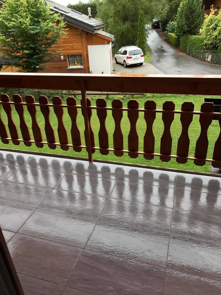 Balcon de chalet carrelé en grès cérame gris, garde-corps en bois massif
