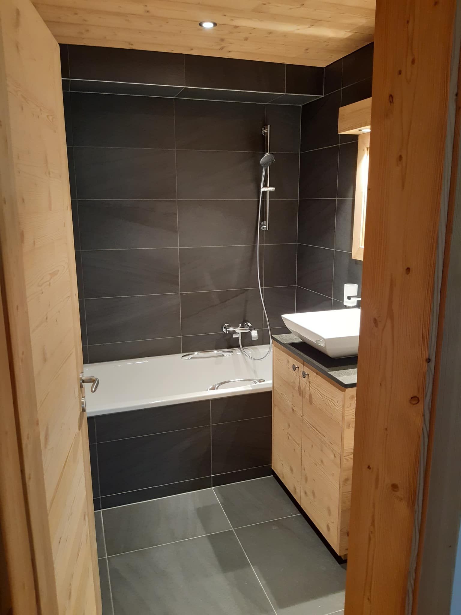 Salle de bains de chalet : grès cérame anthracite, meuble et plafond en vieux bois
